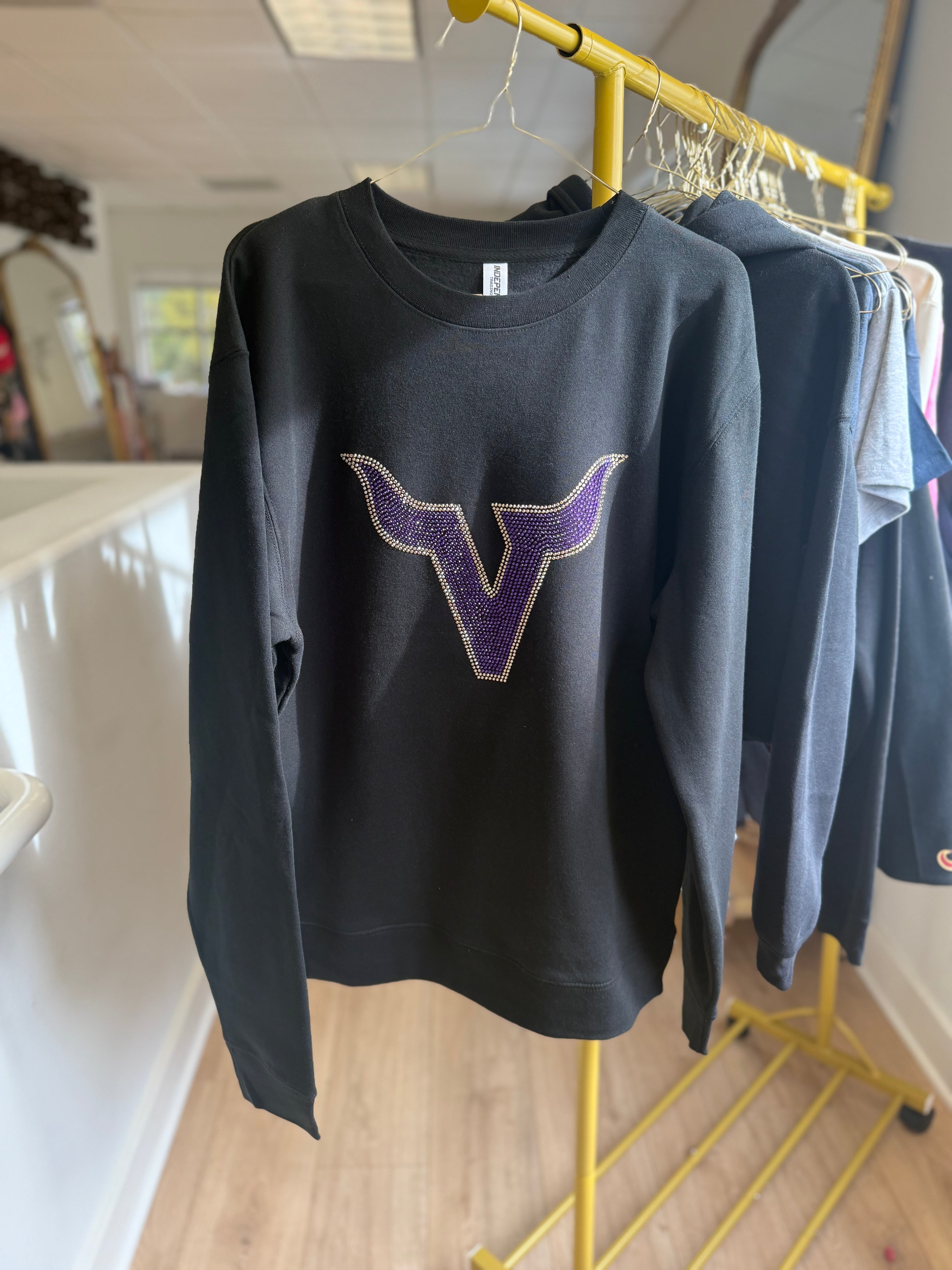 Black sweatshirt with a purple 'V' logo on a yellow rack.